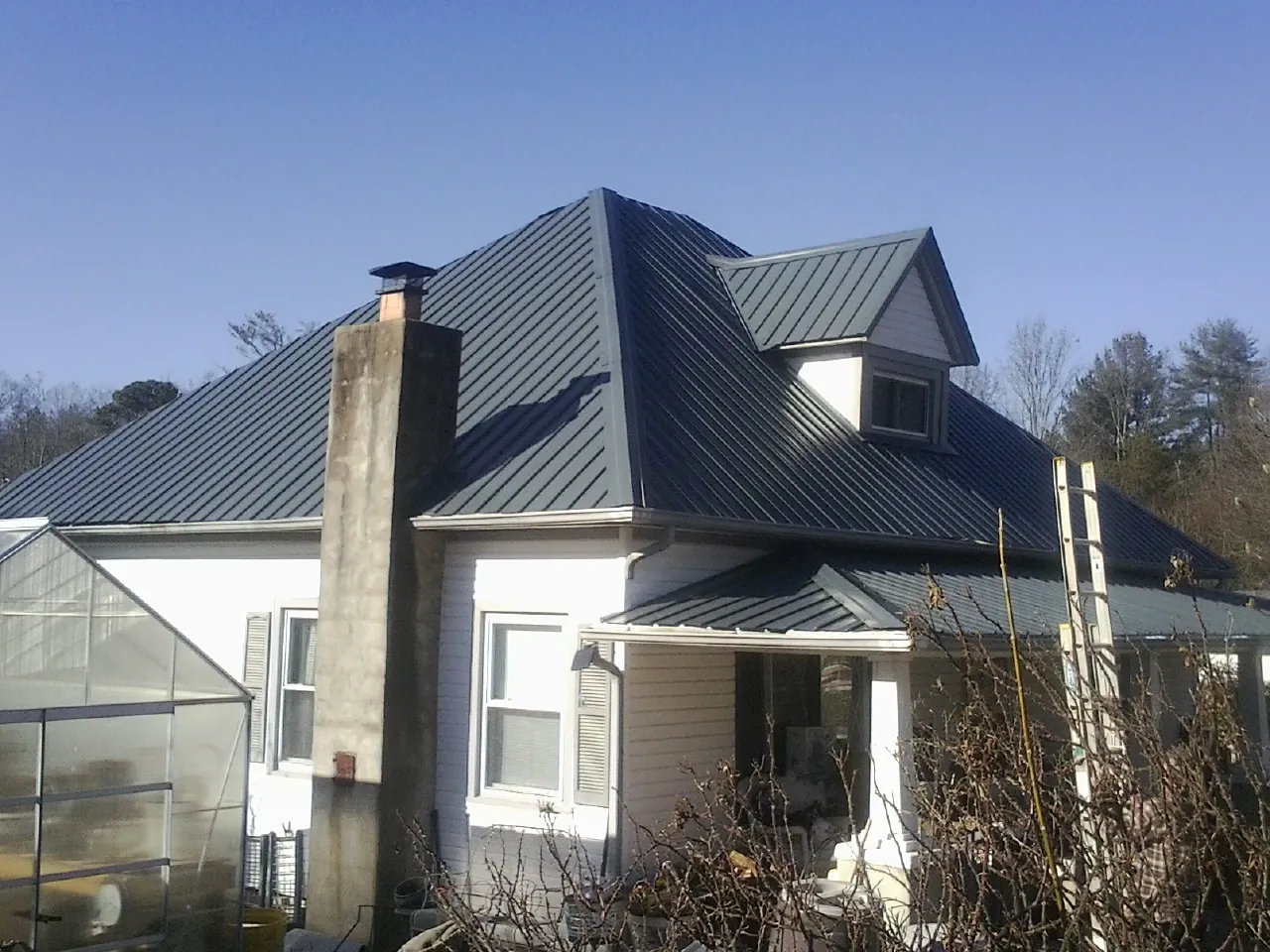 Dark blue standing seam metal roof on a white farmhouse with dormer — Slate & Tile Roof Repair by Roofing Brothers in Parkersburg