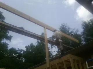 Carpenter setting a ridge beam over a new addition frame — Ice Dam Removal by Roofing Brothers in Parkersburg