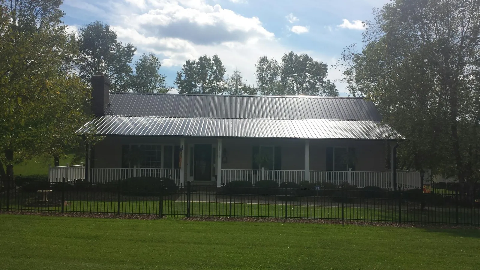 Gray metal roof on a brick ranch with a full width front porch — Gutter Guard Installation work by our crew in Parkersburg