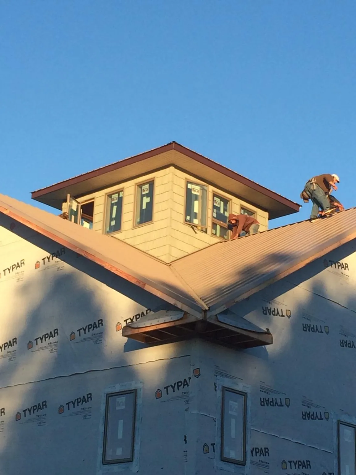 Roofers working around a rooftop cupola on a new metal roof at sunset — Roof Waterproofing in Parkersburg by Roofing Brothers
